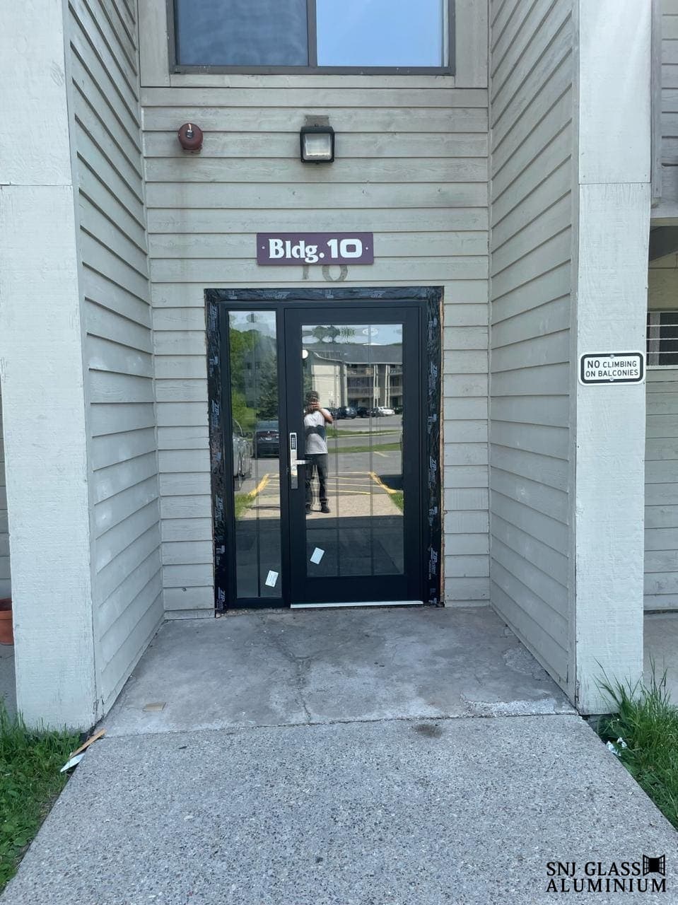 Black-framed glass entrance door with a full-height sidelight.