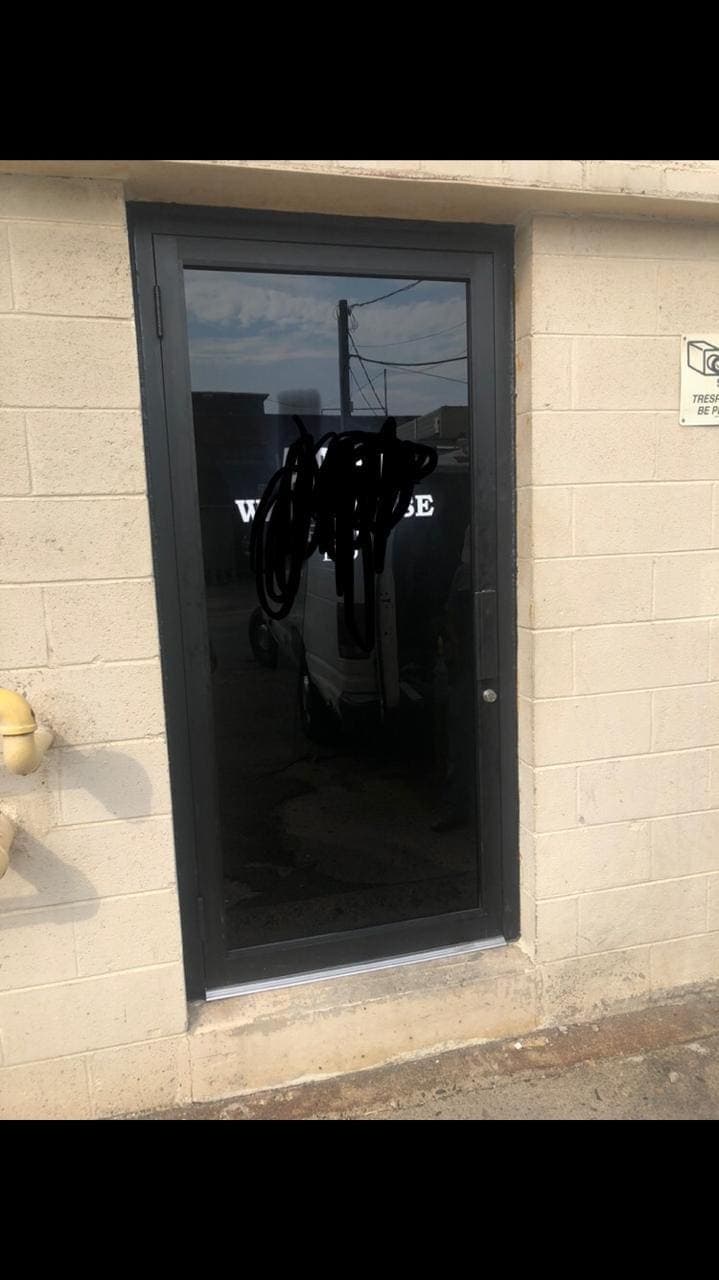 Dark-framed glass entry door set into a masonry wall.