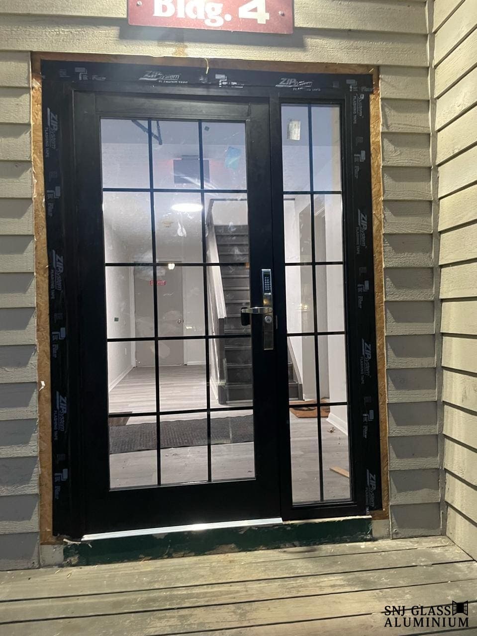 Black grid-style glass entrance door with a matching sidelight.