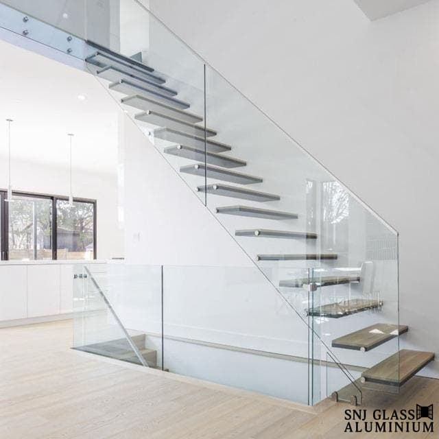 Clear glass railing beside a floating staircase in a bright interior.