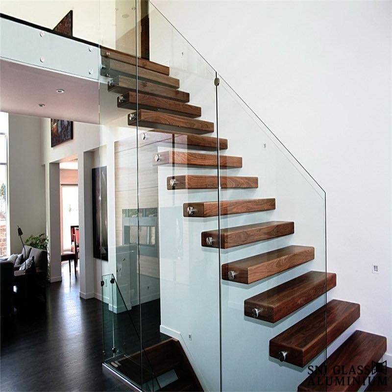Clear glass railing along a wood staircase with floating treads.