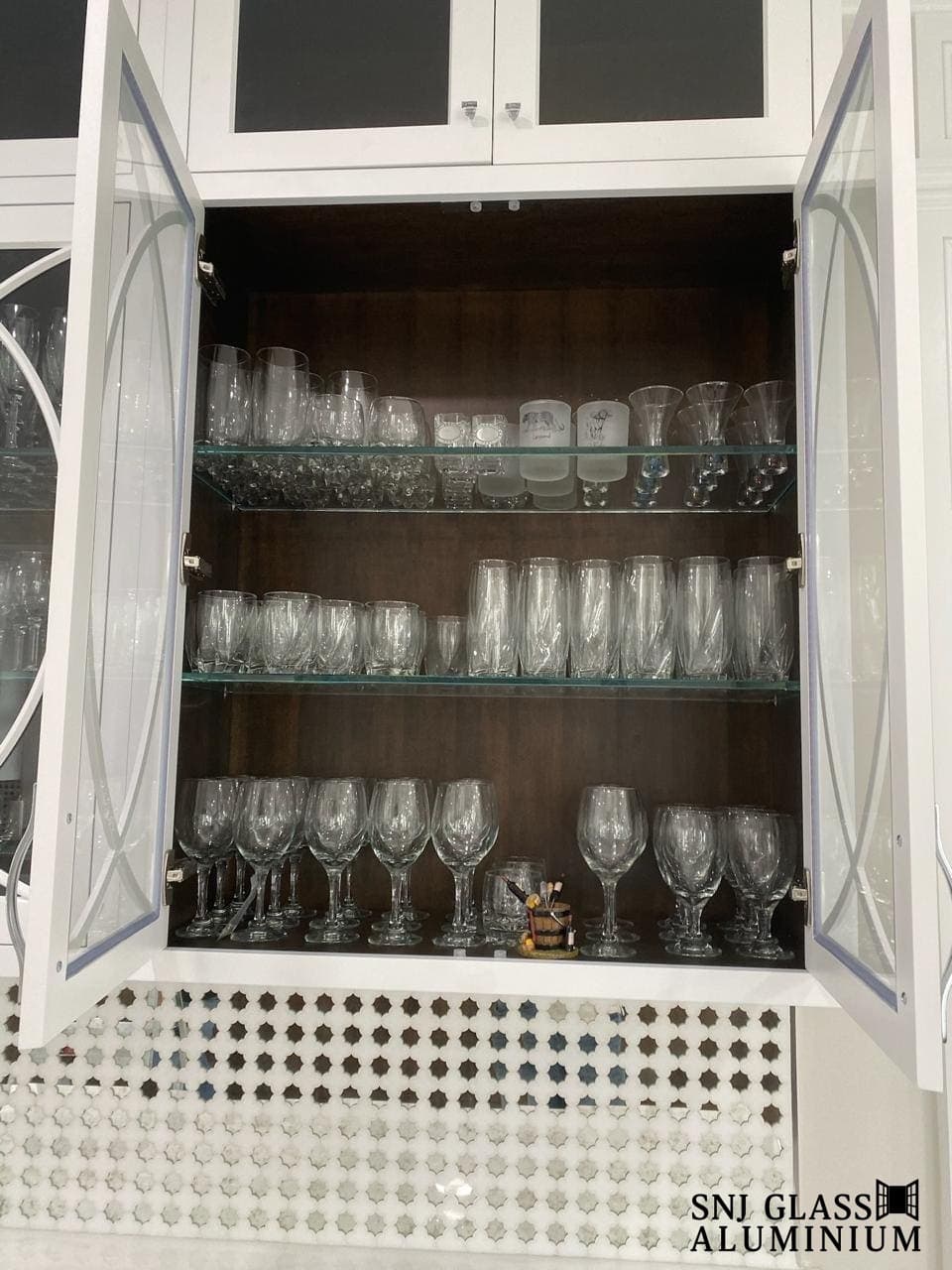 Glass shelves holding drinkware inside a cabinet.