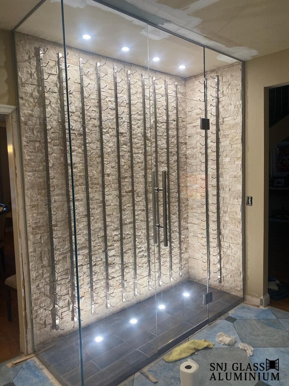 Floor-to-ceiling glass enclosure with vertical bottle racks.