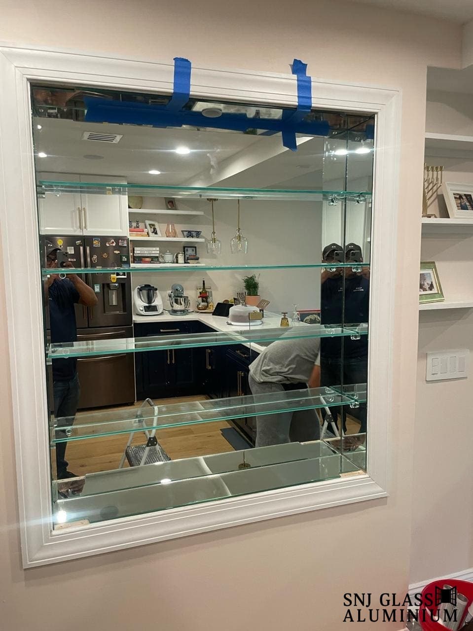 Glass shelves mounted across a mirrored wall opening.