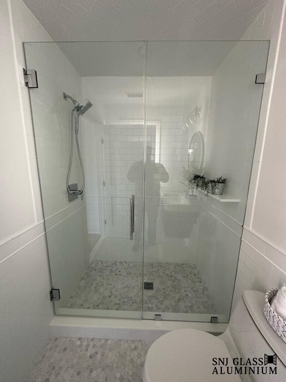 Clear hinged shower enclosure with black hardware and fixed side panels.