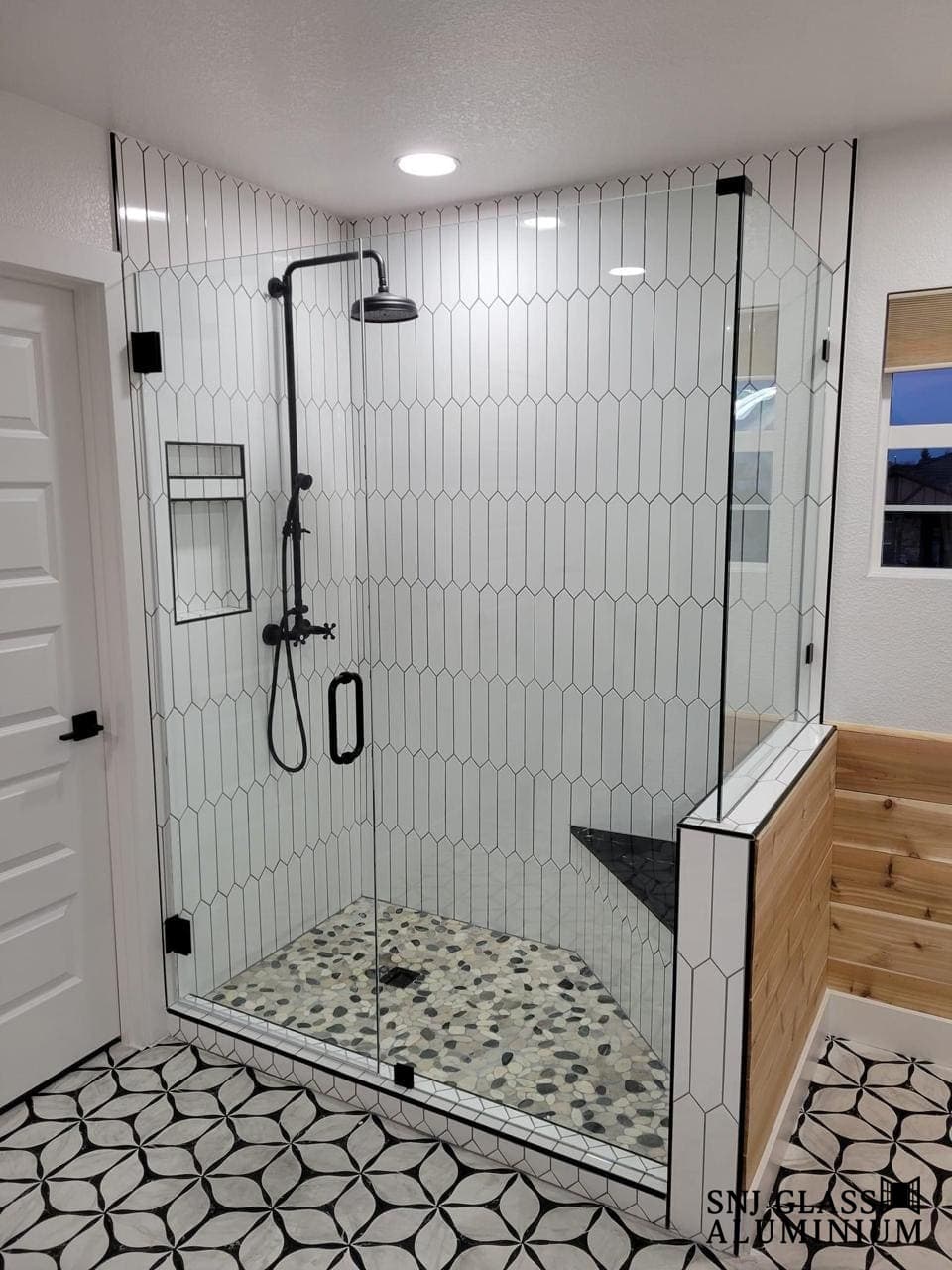 Clear corner shower enclosure with a hinged door and black hardware.