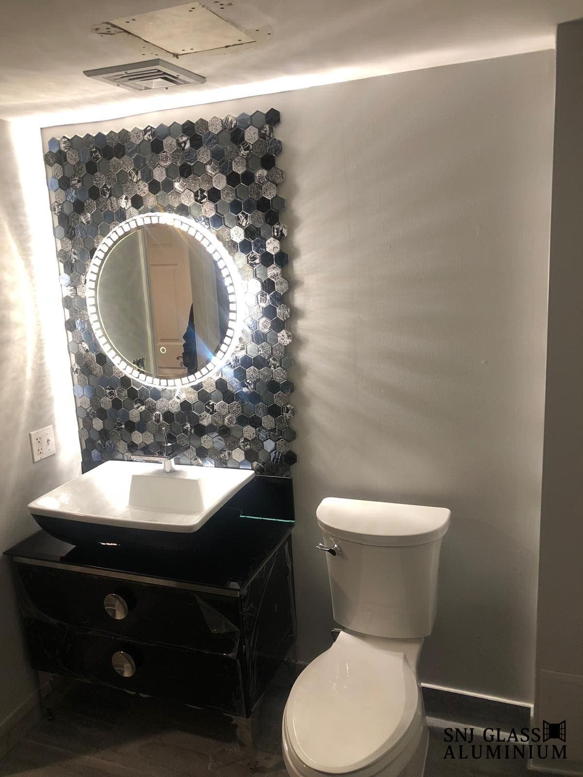 Round illuminated mirror above a bathroom vanity.