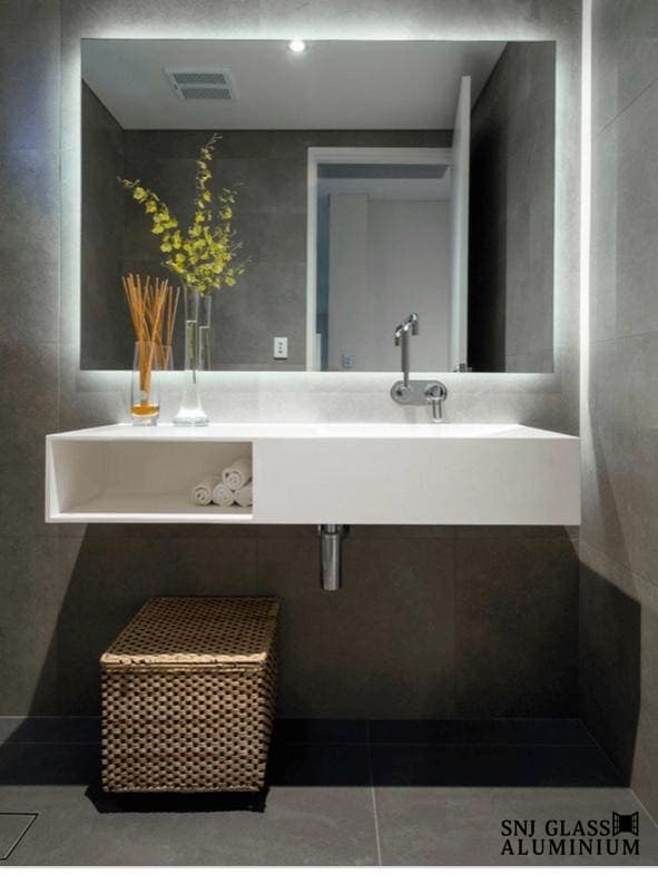 Rectangular illuminated mirror above a wall-mounted sink.