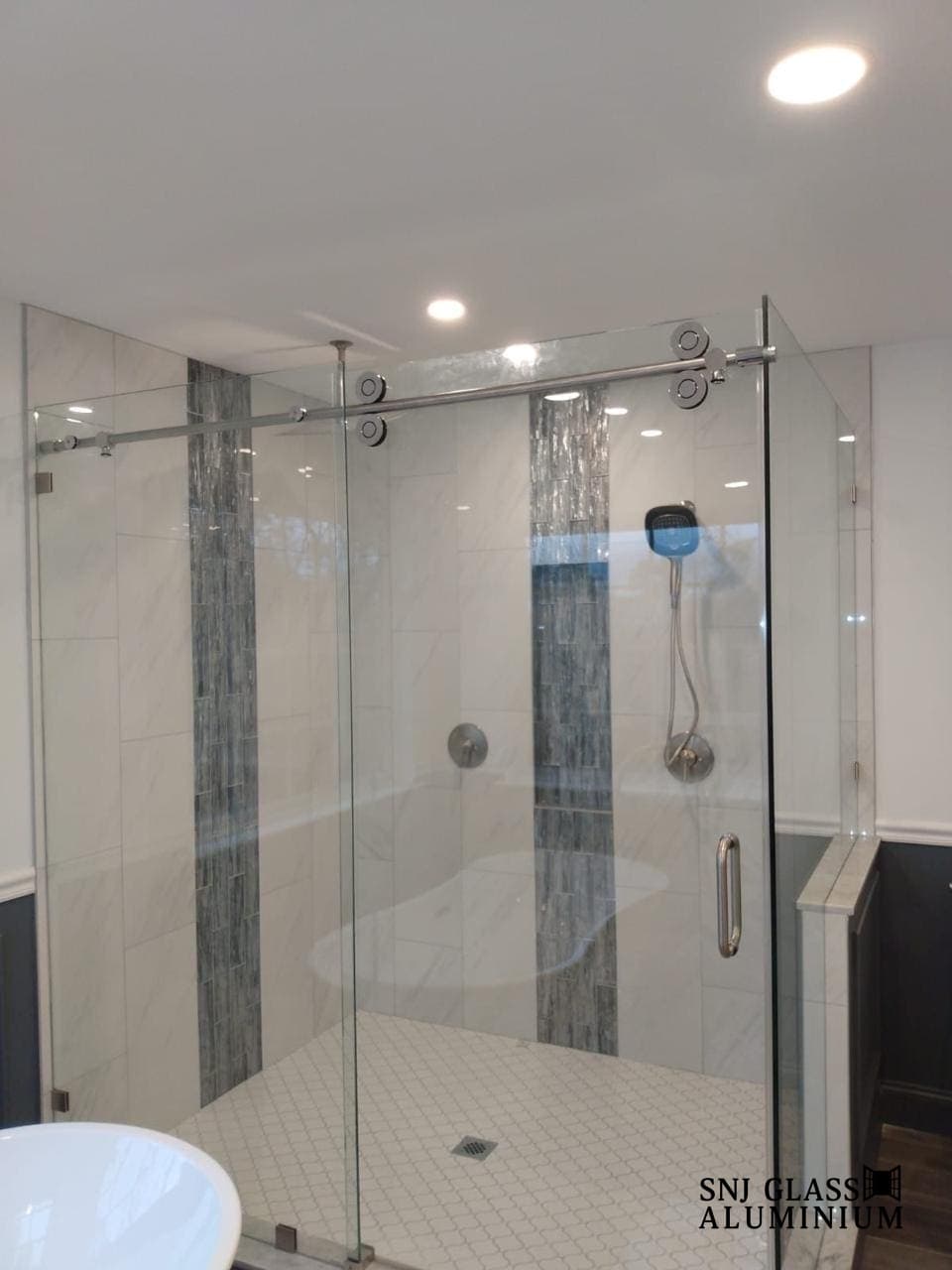 Clear sliding shower enclosure with exposed roller hardware.