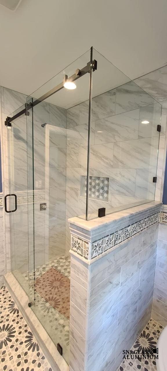 Clear sliding shower enclosure beside a tiled half-wall.