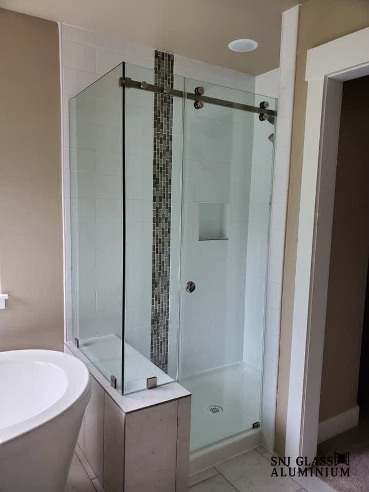 Clear sliding glass enclosure around a corner shower.