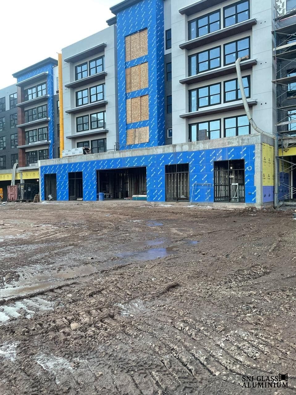Multi-story building facade under construction with installed windows.