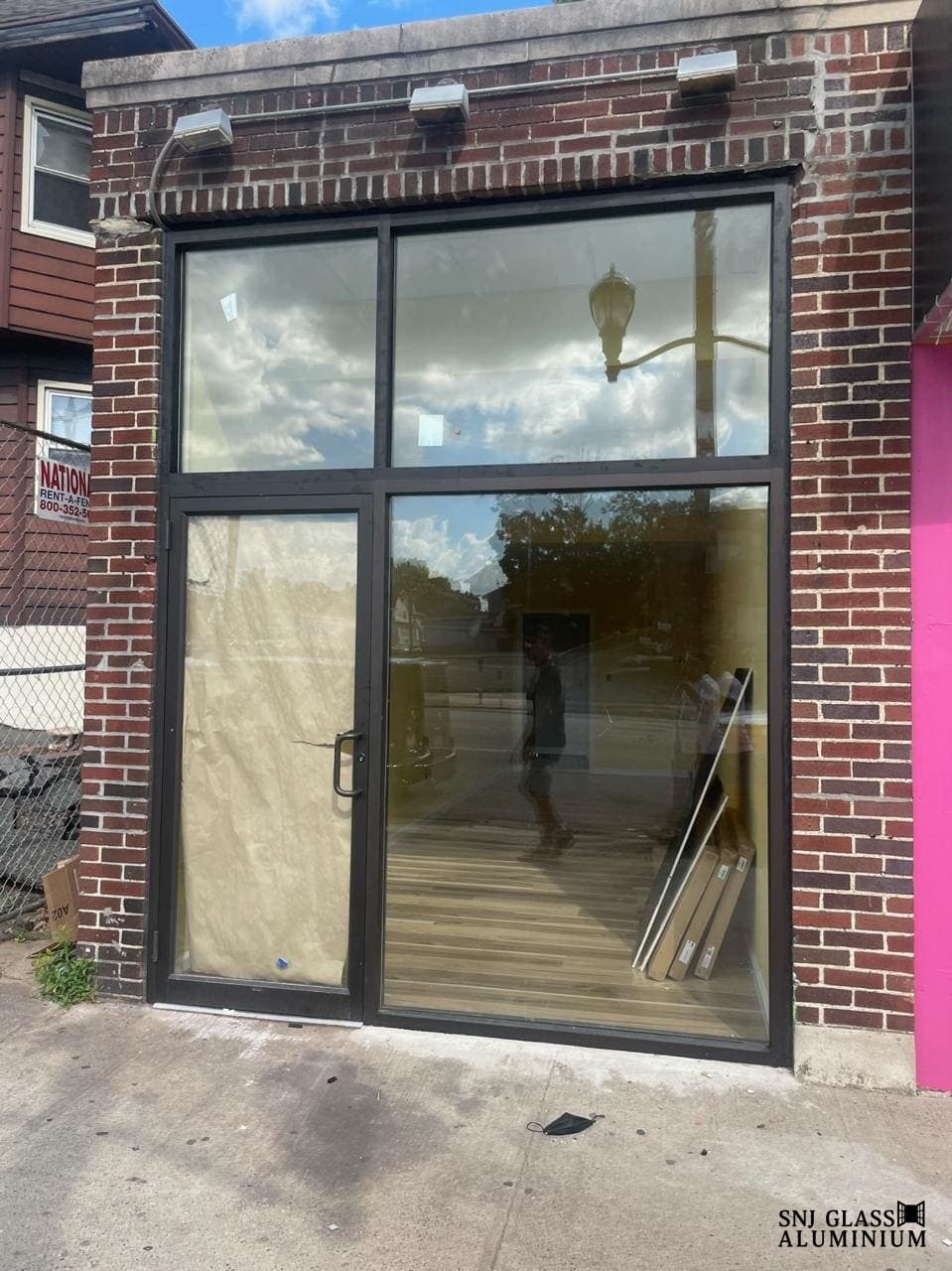 Black-framed storefront glazing and entry in a brick facade.
