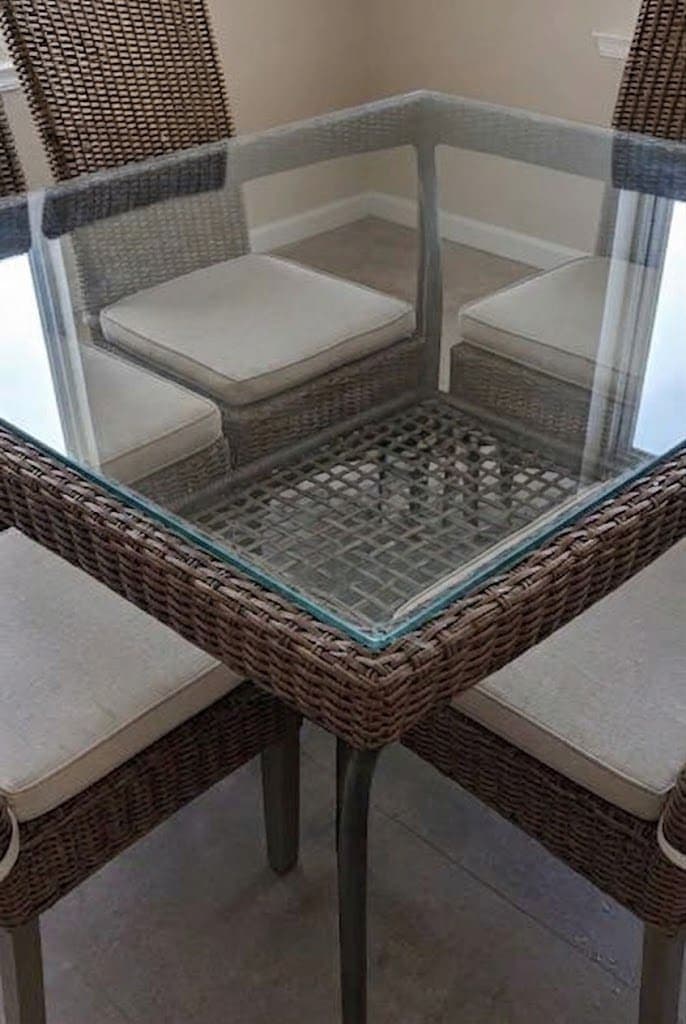 Square clear glass top fitted into a woven outdoor patio dining table.