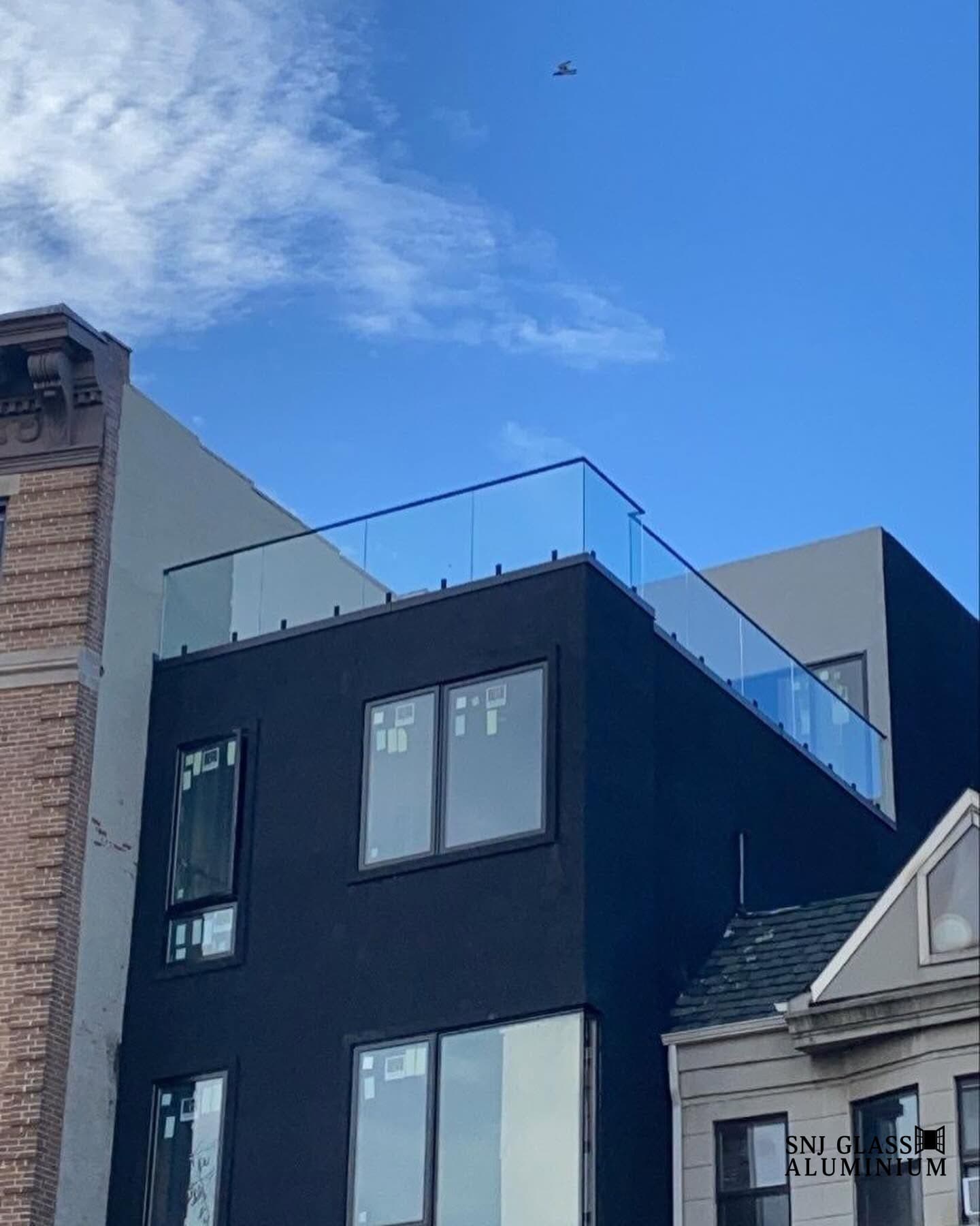 Black-framed exterior windows on a dark multi-story facade beneath a rooftop glass railing.