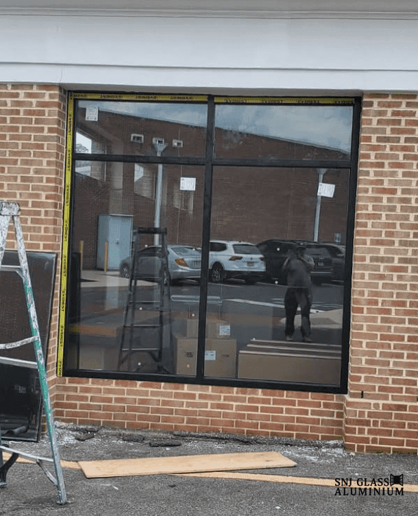 Large black aluminum grid window installed in a red brick commercial facade.