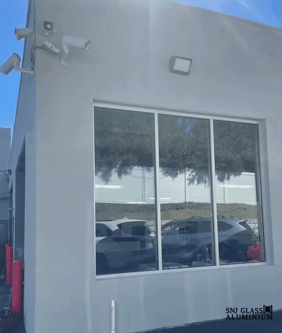 Three-panel window with a silver aluminum frame installed on a gray commercial exterior.