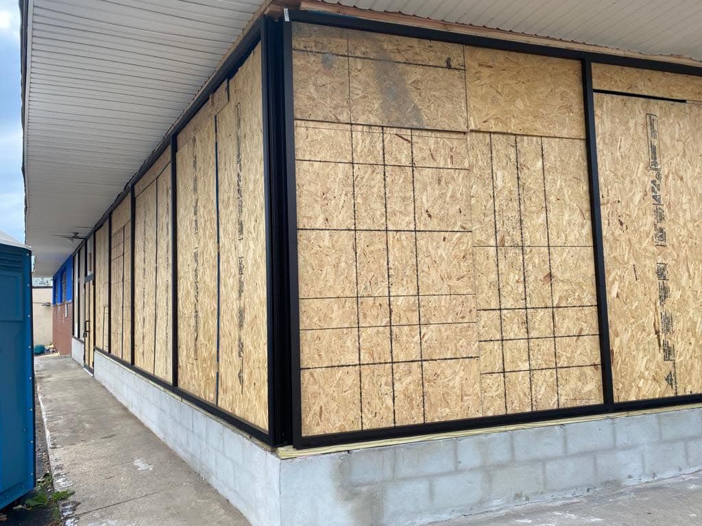 Long commercial elevation with coordinated black storefront openings in Hillside, New Jersey.