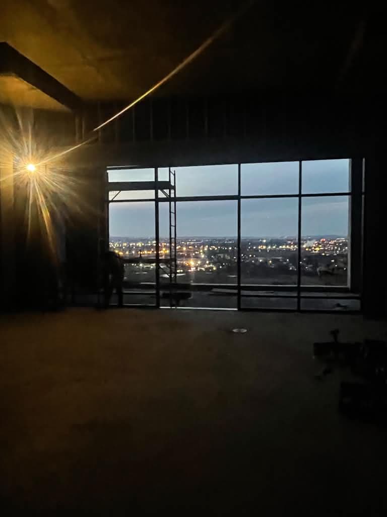 Black-framed window wall overlooking the evening skyline from Cliffside Park.